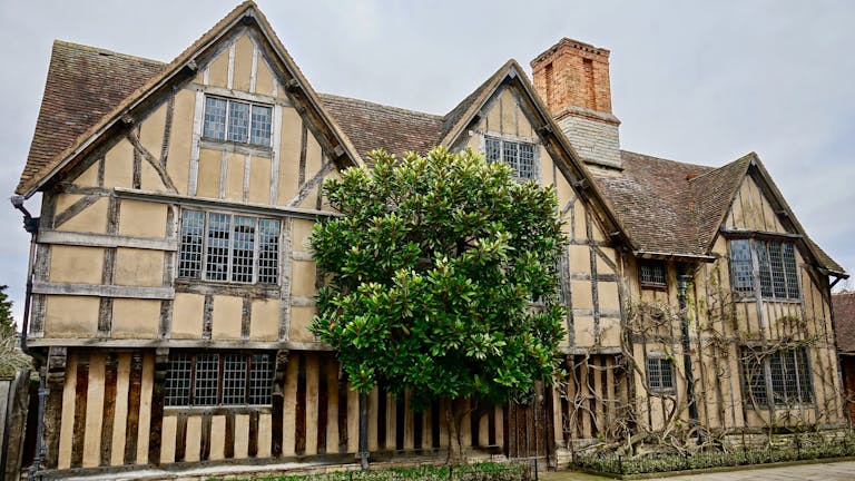 Modern Tudor style house with steep gables, white stucco and black timber accents