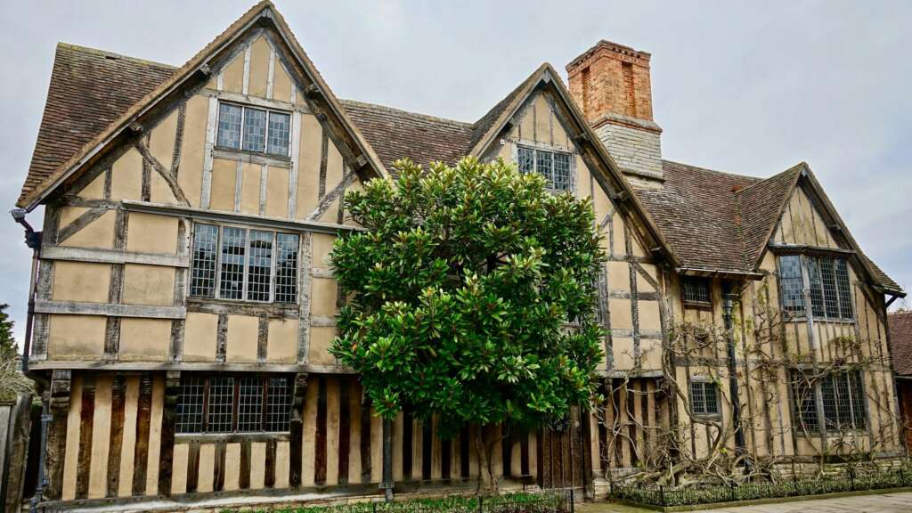 Modern Tudor style house with steep gables, white stucco and black timber accents