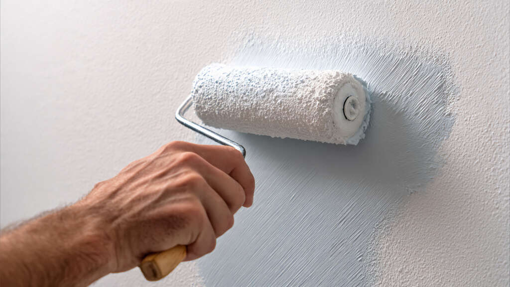 Applying phosphorescent glow in the dark paint to a wall surface with a foam roller